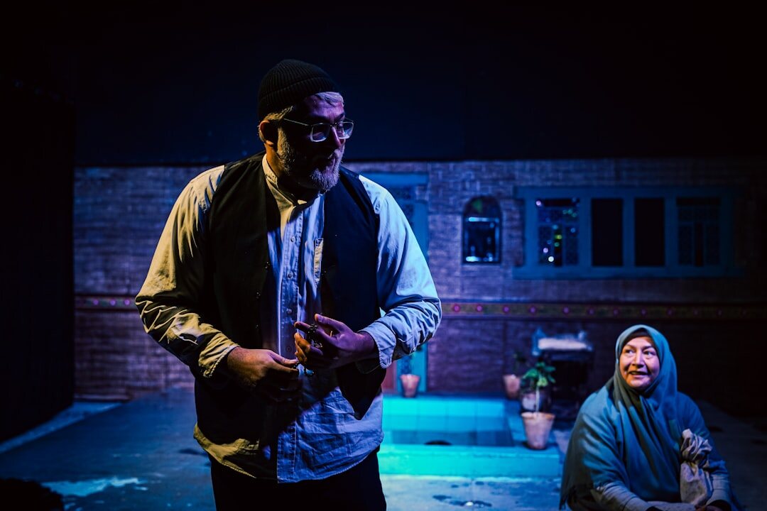 Actor performing a dramatic monologue on a spotlit theatre stage